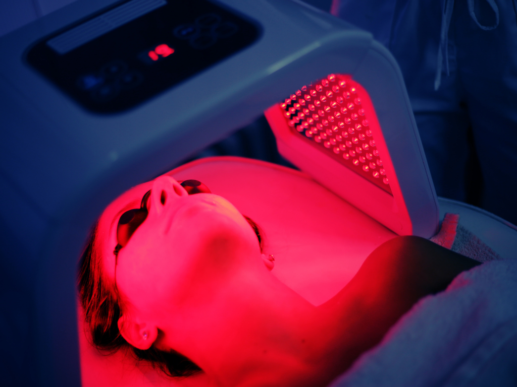 Person lying in a red light therapy bed promoting natural healing and wellness.
